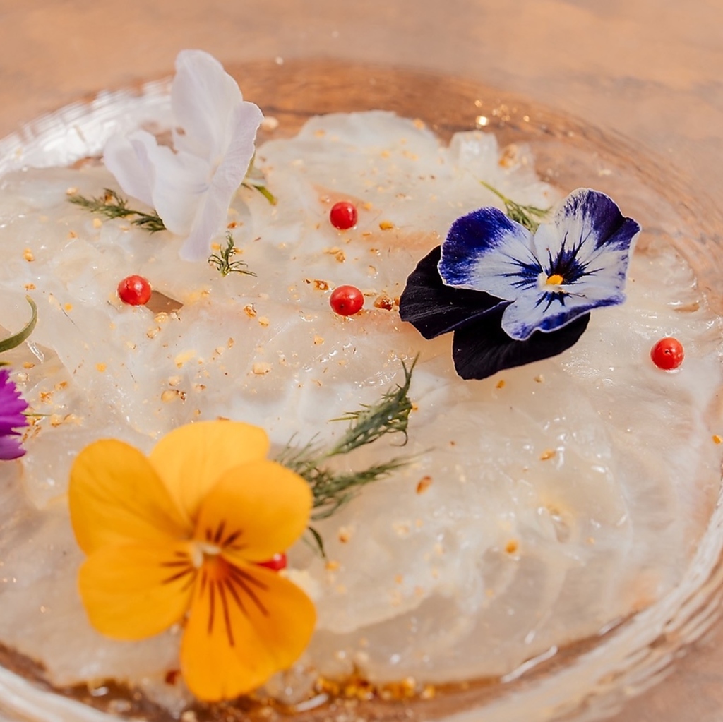新鮮な魚介を華やかなエディブルフラワーで彩った一皿。素材の良さを引き立てる繊細な味わいです。