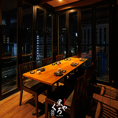 ［3～6名様］外の景色を一望できる、都会の喧騒を忘れさせる空間。木目のテーブルが醸す温もりと、ガラス越しに広がる煌めきが、心を満たすひと時を演出します。大切なご接待や会食など、特別な夜にぜひ。