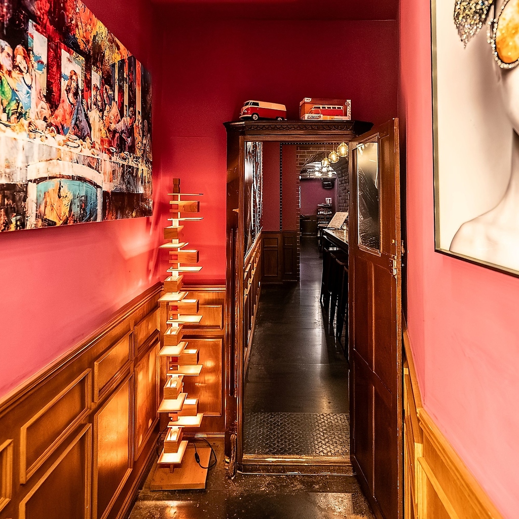 赤い壁と木の温もりが心地よい、秘密の隠れ家のような店内。奥へと続く通路が期待感を高めてくれる。