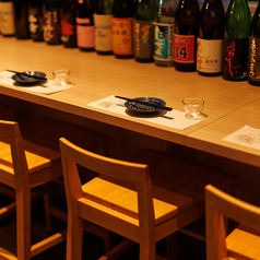 【カウンター席】日本酒ボトルが並べられたカウンター席。このお酒気になる、ラベルがおしゃれ、など会話が弾むかも？！じっくりとお酒やお食事を楽しめるお席です。