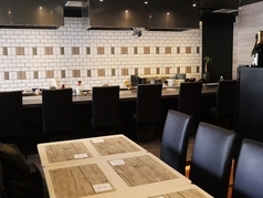 カウンター席越しに調理風景が垣間見えるテーブル席が配置され、ゆったりとくつろげる空間が広がっています。そのワクワク感溢れる調理風景を眺めながら、至福のひとときを過ごすことができます。カウンターからの臨場感とテーブル席でのゆとりあるくつろぎが組み合わさり、心地よいバランスを作り出しています。