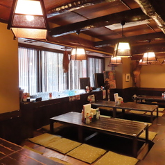 木の温もりが感じられる掘りごたつ席で、ゆったりとした時間をお過ごし頂けます。畳敷きの床と自然光が差し込む大きな窓が、心地よい空間を演出します。調味料やメニューも充実しており、温かみのある照明が雰囲気をさらに引き立てます。