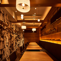 木目の美しい壁面と印象的な和モダンの照明が、心落ち着く雰囲気を演出するテーブル席。両側にハンガーフックも備えられ、会食や仕事帰りの集まりにも快適です。