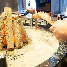 大囲炉裏を囲むように配されたもう一つのカウンター席は、職人のダイナミックな焼き技を最も近い距離で体感できる贅沢なシートです。炭火から立ちのぼる香ばしい香りをダイレクトに感じながら、焼き上がりの瞬間を待つ時間も特別なご馳走。店主との会話も弾みやすく、一人の夜も温かく迎えてくれます。
