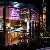 ネオン管の看板が特徴的なガラス張りの開放的な外観で、店内は優しい木目のテーブルや椅子が並ぶスタイリッシュな空間。