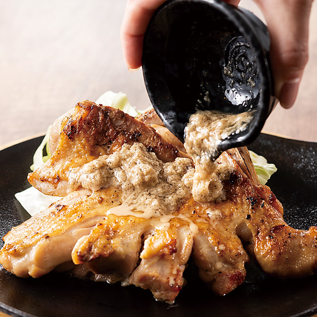 豪快に焼き上げた清流若どりのもも1本焼きは、シェアにぴったりの名物料理！特製玉葱塩ダレが決め手