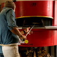イタリア製の本場薪釜専用ピザ釜で、職人が焼き上げます。