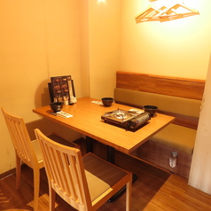 木の温もりに包まれた店内には、清潔感のある明るい色調のテーブル席が並びます。壁側はゆったりと寛げるベンチシートになっており、各席にはコンロが完備されています。竹のカーテンが適度なプライベート感を演出し、落ち着いて食事を楽しめる空間です。