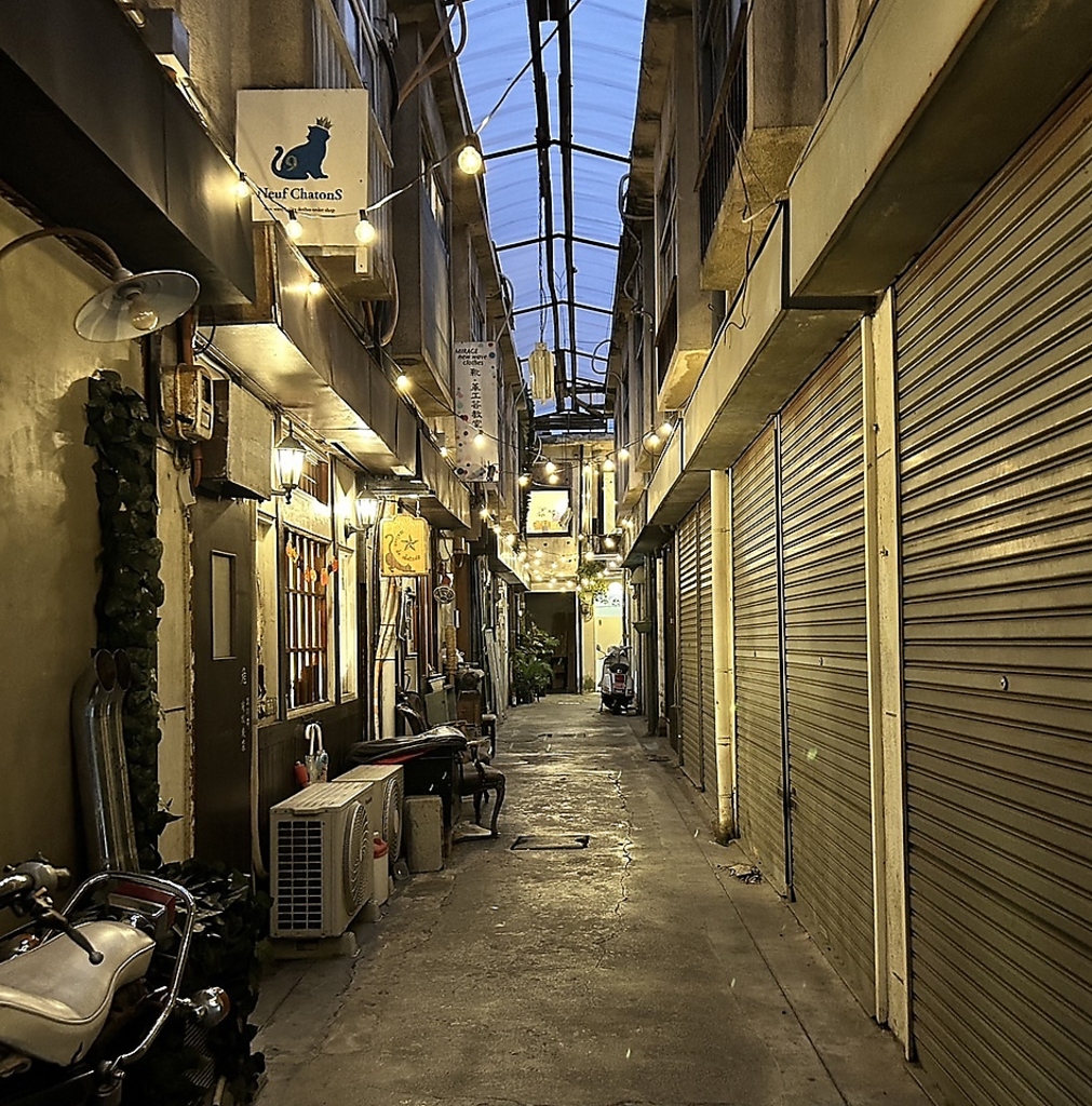 繊維街の趣のある通りを歩けばお店へ上がる2階踊り場部分に目印となる凹凸Tacosの看板がございます。