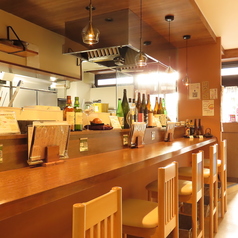木目調の落ち着いた雰囲気の店内。キッチンに面したライブ感溢れるカウンター席をご用意しております。お一人様でゆっくりとできるよう椅子と椅子の空間を広めに空けております。暖かみのある照明の下で、ゆったりとした時間をお過ごしください。様々なシーンでのご利用をお待ちしております。