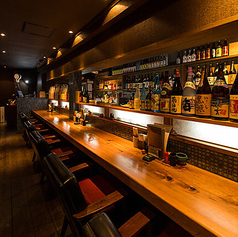 艶やかな一枚板のカウンターには、ソファのように柔らかく幅広の椅子が並び、居心地の良い空間を演出しています。おひとりで静かに飲むのも、仲間と肩を並べて語り合うのも最適です。リラックスした雰囲気の中で、特別なひとときをお楽しみいただけます。心地よい時間をぜひご堪能ください。