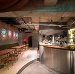 コンクリートの壁とシンプルなインテリアが調和し、洗練されたモダン空間。多彩な料理をお酒とともに