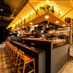 【1F:カウンター席】フルオープンキッチンを目の前に構えるカウンター席は、まさに“ライブキッチン”の特等席。焼き上がる音、立ち上る香ばしい香り、シェフの手さばき、そのすべてが、料理を待つ時間さえ至福に変えてくれます。名物・炉端焼きが目の前で仕上がる様子は、まさに外食の醍醐味。