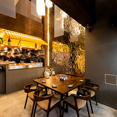 【1F:入り口付近テーブル席】エントランスすぐの1階テーブル席（1～2名 × 3卓）は、天井の吹き抜け空間を活かした開放感あるレイアウト。頭上にはプロジェクションマッピングが幻想的に映し出され、まるでアート空間に足を踏み入れたような感覚に包まれます。料理とともに、視覚を彩る演出が特別なひとときを演出。