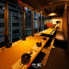 ［16～20名様：半個室］大きな窓から望む夜の街並みに、粋な和の意匠が彩りを添える団体様向けの半個室。木目のテーブルと落ち着いた照明が、静けさと温もりを感じさせ、ご宴席にふさわしい空間です。