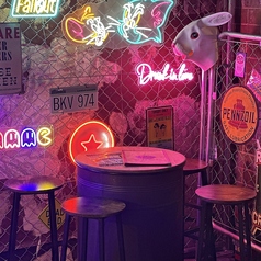 【テーブル席】レトロなコンクリートネオンの壁が印象的なテーブル席は、ネオンのランプにアメリカンガレージと、レトロな雰囲気が漂う店内で楽しいひと時を。