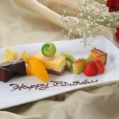 チョコレートケーキやチーズケーキ、季節のフルーツを美しく盛り合わせた、華やかなデザートプレート。チョコレートメッセージで、お祝いの気持ちをさりげなく演出します。誕生日や記念日など、特別なひとときにぜひご利用ください。