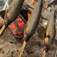 囲炉裏で焼く串刺しの魚、肉や野菜の炭焼き