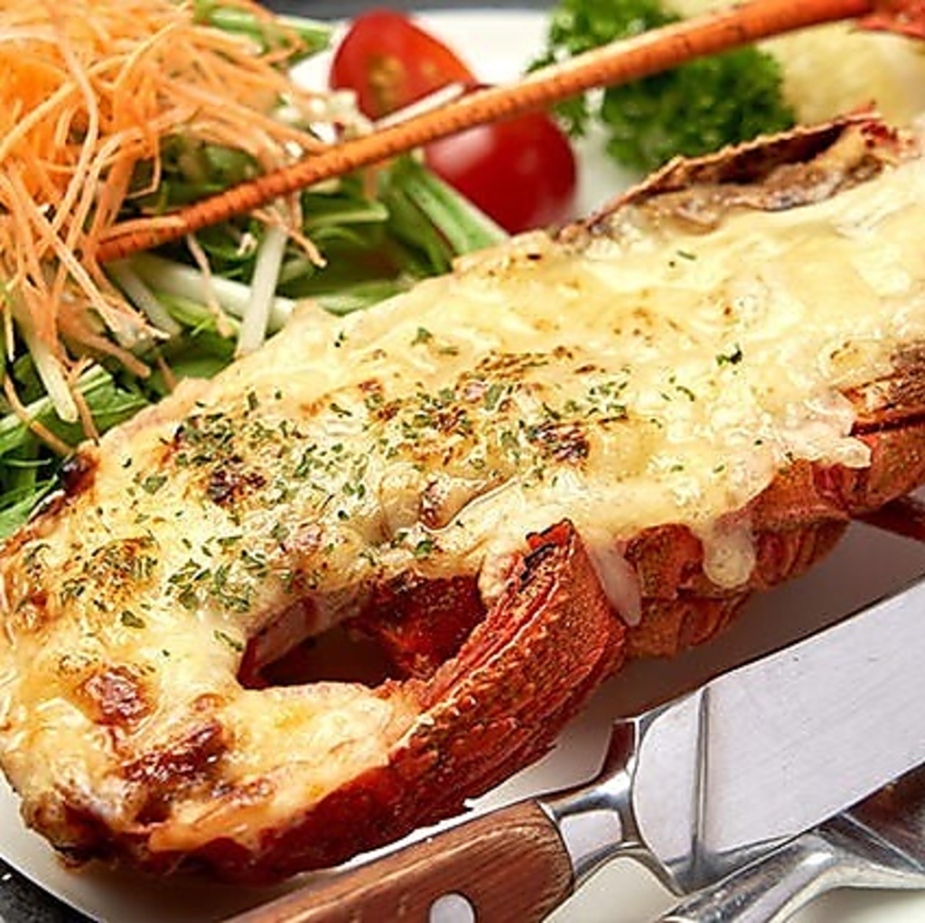 ［伊勢海老チーズ焼き］ 伊勢海老の半身にチーズをのせてオーブンで焼き上げた逸品。