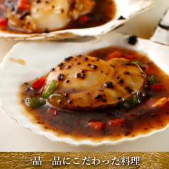 【料理長自慢の逸品】大粒ホタテの芳醇な旨味を引き立てる！香ばしい特製トウチソースが絡む絶品殻付き帆立の写真