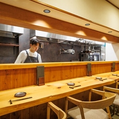 温かみのある木の質感が美しいカウンター席と、オープンキッチンが目を引く店内。厨房では職人が真剣な眼差しで料理に向き合い、ライブ感と特別感を演出しています。一皿一皿に心を込める手さばきを間近で眺めながら、自慢の料理と厳選したお酒をゆったりと堪能できる、贅沢な大人好みの特等席です。