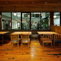 シンプルな木製のテーブルとチェアが並ぶ、開放的な窓際のエリアです。柔らかなライトが温かい雰囲気を演出します。開放感がありながらも、隣席との間には適度な仕切りがあり、ご家族でのご利用にもおすすめです。