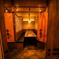 木目調の壁と暖簾が落ち着いた雰囲気を醸す和風個室。温かみのある照明の下、ゆったりとした空間で本格料理と地酒を楽しめます。