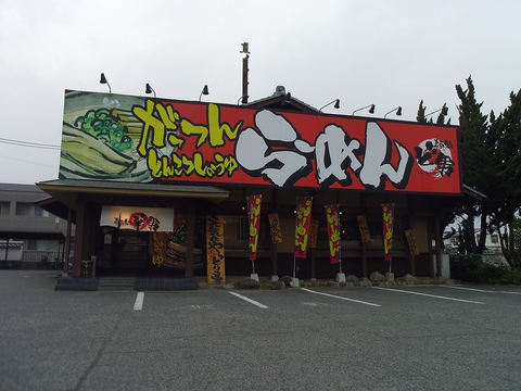 赤い大きな看板にラーメンの文字が目立つ店舗。こだわりのとんこつラーメンはここで！