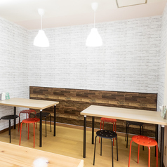 4名様用テーブル席は、白レンガ調の壁紙が明るい印象を与える、清潔感あふれるスペースです。赤と黒のモダンなスツールがアクセントとなり、友人とのランチや女子会、ご家族でのティータイムなど、様々なシーンでカジュアルに心地よく過ごせる空間となっています。