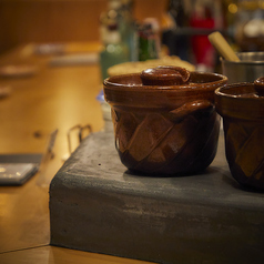 照明を抑えた店内に並ぶのは、存在感ある無垢のカウンター席。SAKABA 博多炉端つまむでは、調理の様子を間近で楽しめるカウンター席が全て。藁焼きの瞬間に立ちのぼる煙と香りが、非日常へと誘ってくれます。