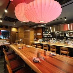 木の温もりを感じる落ち着いた店内。カウンター席では調理のライブ感を楽しめ、テーブル席は仲間との食事に最適。赤いランプが灯るおしゃれな空間で、宮崎地鶏の炭火焼きを堪能できます。