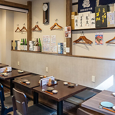 木の温もりが心地よい和風空間。壁には日本酒のラベルが並び、落ち着いた雰囲気が広がります。ゆったり配置されたテーブル席で、隣を気にせず食事と会話を楽しめます。広めの通路で移動も快適です。