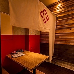 【テーブル席（半個室）：2～8名様】周りを気にせず楽しめる、テーブル席の半個室（4名様席を2卓ご用意）。2名様から最大8名様までご利用可能です。入り口の暖簾（のれん）をくぐれば、木の温もりと赤い差し色が印象的な和空間が広がります。ご友人との語らいや少人数の宴会にぴったりです。