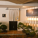 居酒屋「夢」で至福のひと時を。落ち着いた店構えと立派な盆栽が、大人の隠れ家へと優しく誘います。