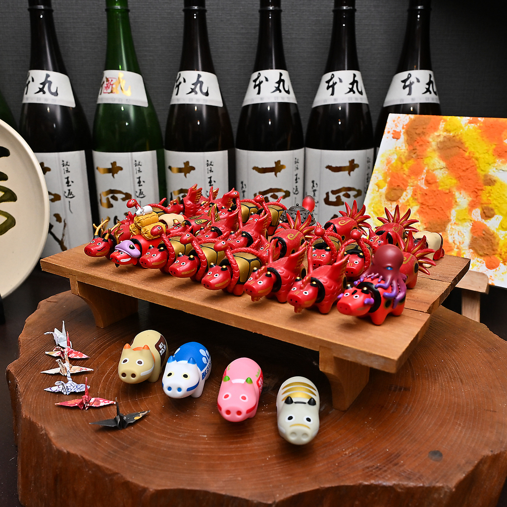 銘酒、十四代が並ぶ贅沢な空間。愛らしい赤べこと折り鶴が彩る、遊び心溢れる店内で至福のひと時を。