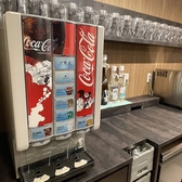 店内には「セルフ飲み放題」専用のドリンクコーナーを設置！コカ・コーラ、メロンソーダ、カルピス、ジンジャーエールなどの定番ソフトドリンクが揃うディスペンサーから、お茶類まで充実のラインナップ。お酒を飲まない方やお子様も、自分の好きな飲み物を好きなだけ楽しめる、自由で活気あふれる設備となっています♪