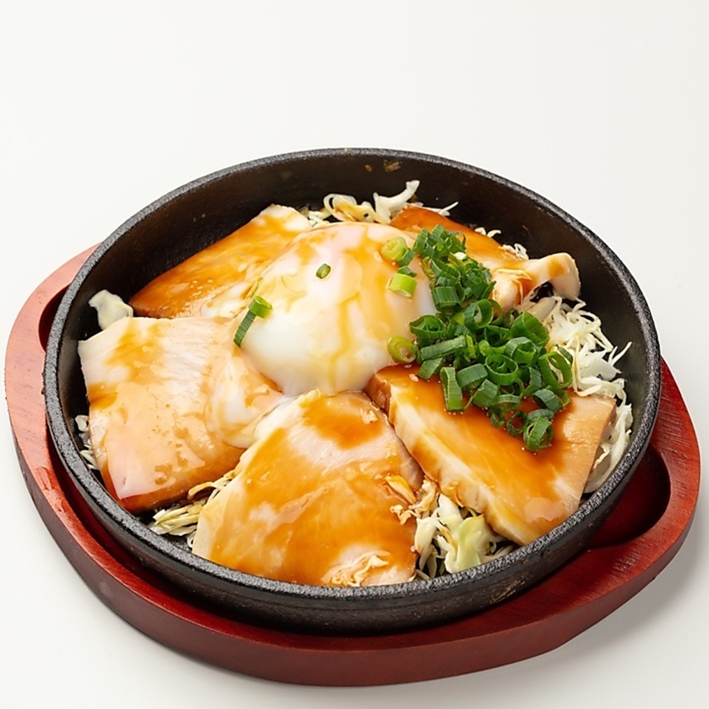 熱々の鉄板で焼くチャーシューエッグ。とろける卵の黄身を濃厚なタレに絡めて食べるのが醍醐味。