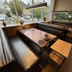柔らかな光が差し込む窓際のボックス席。ゆったり座れるソファー仕様で、カップル・友人同士・ご家族まで幅広く利用しやすい人気の席です。温かみのある木のテーブルと外の景色が相まって、落ち着いた食事の時間を演出します。プライベート感があり、会話もしやすい安心の空間です。