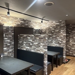 木の温もりと落ち着いた照明に包まれたテーブル席。仕切り付きで周りを気にせず食事を楽しめる空間。