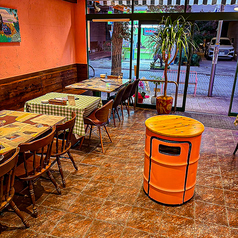 木の温もりあふれるテーブル席は、カジュアルながら落ち着いた雰囲気。オレンジの壁が柔らかく照らし、自然と会話も弾む心地よさです。