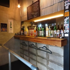 【立ち飲みカウンター席】無機質なコンクリートと温かな照明が調和する立ち飲みカウンター。ライブ感溢れる空間で、サクッと一杯楽しむのに最適です。