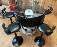 ハマーH1のタイヤを天板にした手作りテーブルです。タイヤの中にはカワサキのオートバイのタンクなどをディスプレイしています。カウンターチェアを6脚設置しています