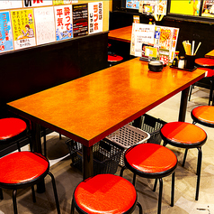 木目のテーブルと赤い丸椅子が並ぶ、大衆酒場らしい温かみのあるテーブル席。足元には荷物カゴも完備しており、ゆったり座って食事やお酒を楽しめる人気のエリアです。仲間同士の飲み会にも使いやすく、自然と会話が弾む居心地の良さが魅力。