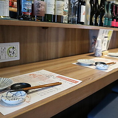 目の前の棚に酒瓶がずらりと並ぶカウンター席をご用意しております！卓上には小皿や小鉢、箸が敷紙の上にセットされており、落ち着いてお食事をお楽しみいただける空間です◎「九条ねぎ」と書かれたPOPも掲示されており、お店のこだわりが感じられます♪ご友人同士や、お仕事帰りの一杯にもぜひお気軽にご利用ください！