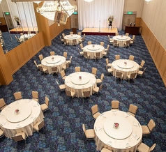 大宴会場を3分の1利用したセッティング例です。約100名様規模のご宴席に対応し、立食パーティーや着席ビュッフェ、正餐スタイルなど多彩な形式でご利用いただけます。ステージや音響設備の設置も可能。株主総会やお祝い会、歓迎会、卒部式など企業やスポーツ団体のお集まりにも幅広く対応いたします。