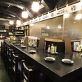 黒を基調としたシックな長机と温かみのある照明が、大人の隠れ家のような落ち着いた雰囲気を演出するカウンター席です。