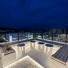 【テラス:テーブル】テラス壁側の席は、夜景をガラス越しにゆったり望める隠れ家ポジション。足元の間接光が柔らかく灯り、会話に集中できる静けさも魅力。写真映えはもちろん、デートに最適な特等席です。