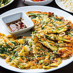 本場の味を再現！たっぷりのネギと海鮮が魅力の海鮮チジミ。甘辛タレで楽しむ韓国の味わいの写真