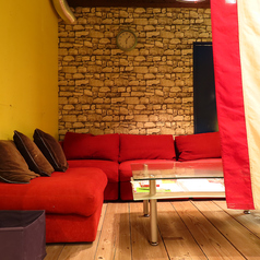 【落ち着く空間】温かみのある赤いソファに囲まれたリラックススペースです。大きなガラスのテーブルがあり、友人や家族との会話を楽しむのに最適な居心地の良い空間です。