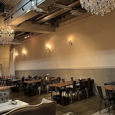 【2名様～6名様用】開放感あふれるテーブル席。頭上にシャンデリアが輝き、白いレンガの壁とモルタルを組み合わせた開放感あふれる空間で、 ごゆっくりお食事をお楽しみいただけます。